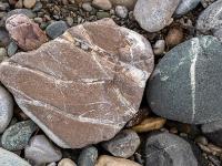 Hellbrauner Stein mit dünner weißen Maserung und Riefen neben grauem Stein mit weißer Mittenmaserung